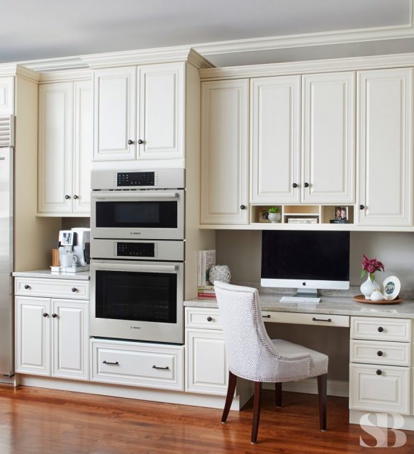 cream cabinets with computer workspace and oven