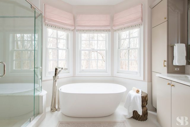 white standalone bathtub with pink window treatments