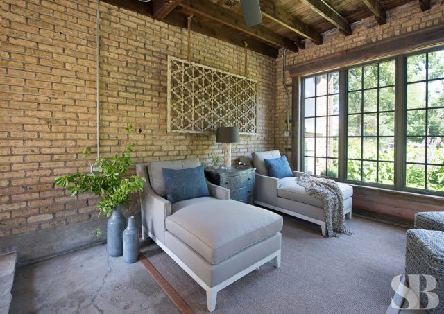 room with two grey chaise lounges and a brick wall