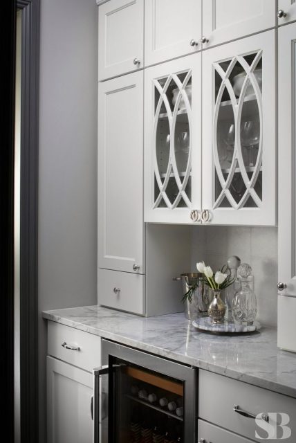 Kitchen bar area with marble countertops and white wine glass cabinets