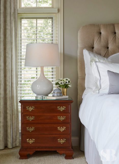 close up of upholseted headboard and wooden nightstand with lamp