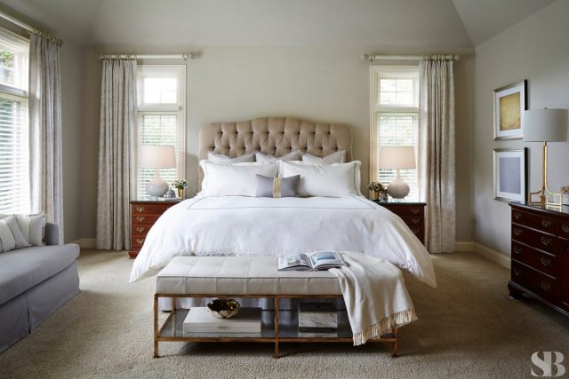 master bedroom with white sheets and upholstered headboard and bench
