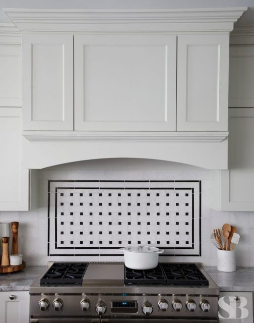kithcen stove range with white cabinet hood and rectangular tile backsplash